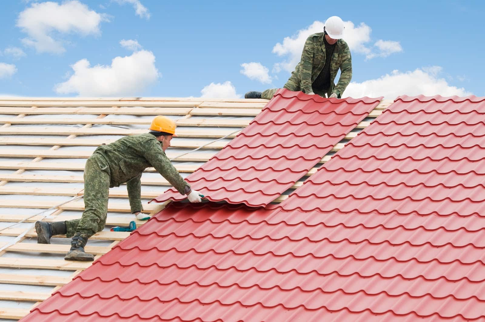 Two workers on roof at works with metal tile and roofing iron